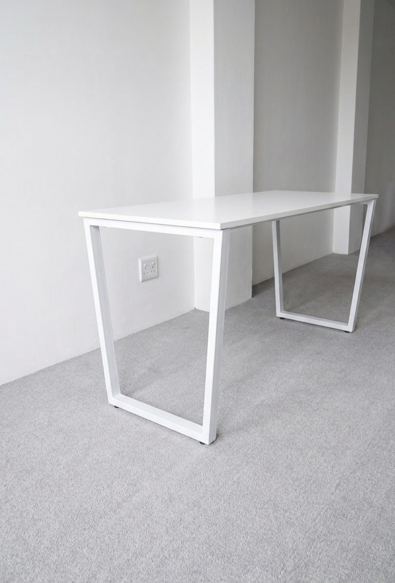 White desk against a plain white wall with a light gray floor.