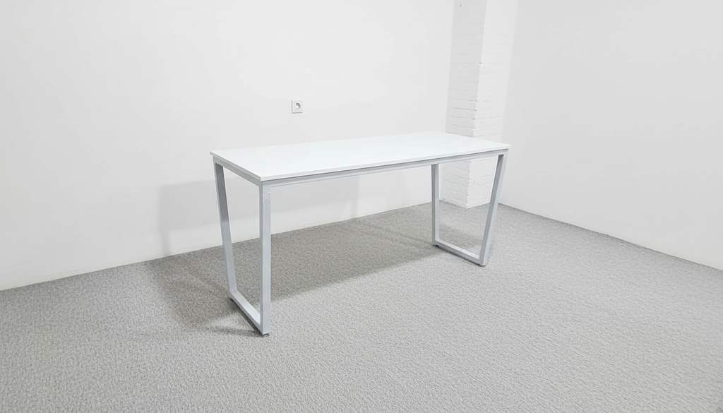 White office desk in a minimalistic room with white walls and gray floor.